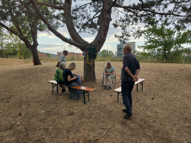 Abendgottesdienst bei der Umweltstation: Gottesdienstbesucher:innen sitze unter einem Baum.