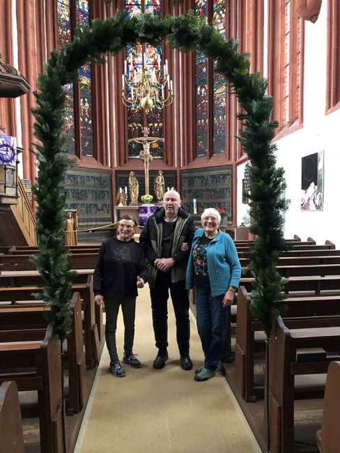 Mit Tannengrün geschmückter Bogen im Hauptgang der Deutschhauskirche mit den Personen, die ihn gebunden haben.