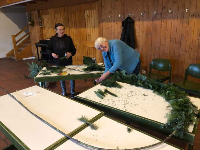 Zwei Frauen binden das Tannengrün um den eisernen Bogen im Remter.